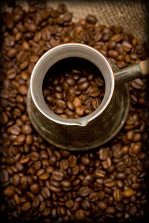 Cezve with freshly roasted coffee beans on sackcloth. Shallow depth of field. Focus on cezve throatの写真素材