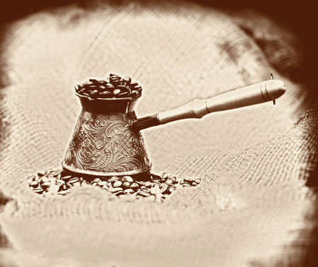 Vintage image background with old-style cezve with coffee beans on sackclothの写真素材