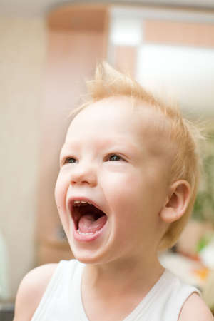 Screaming happy boy with funny hairstyle at home