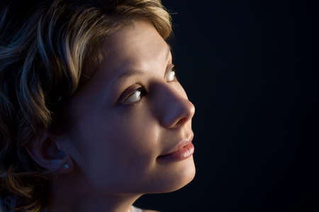 Portrait of pretty blond girl looking up over black with blue illuminationの写真素材