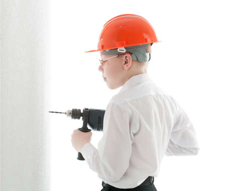 Teenager in protective helmet and spectacles drill the wallの写真素材