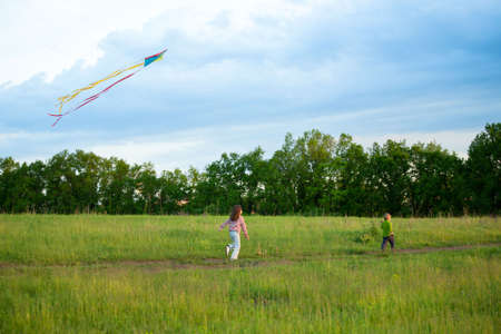 Two kids running on a meadow and fly a kiteの写真素材