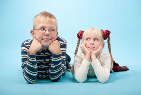 Portrait of a brother and sister lying down on floorの写真素材