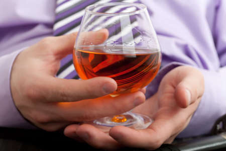 Hands with glass of cognac. Focus on hand with glassの写真素材