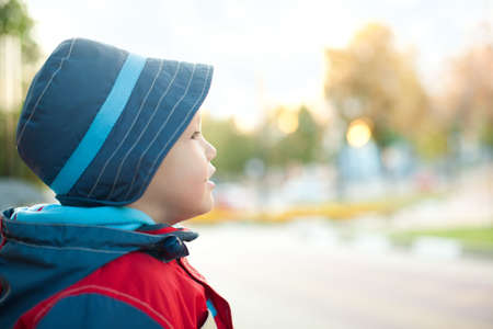 Dreaming boy in hat and wind-cheater outdoorの写真素材