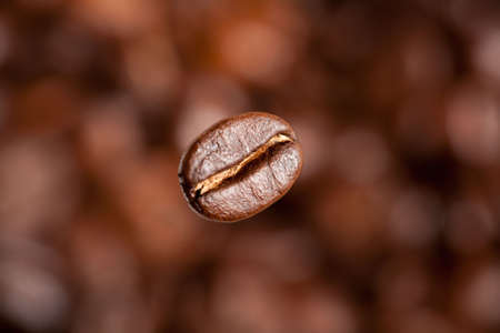 Freshly roasted coffee beans. Shallow depth of field. Focus on flying beansの写真素材