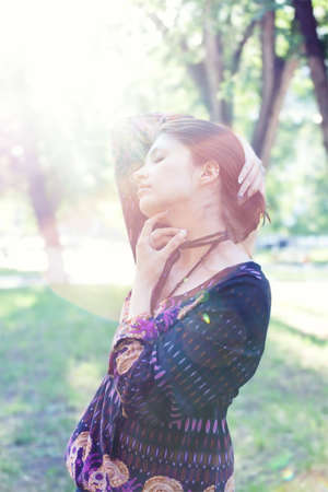 Young woman enjoys sun beams at spring park. Lens flares and low contrast.の写真素材