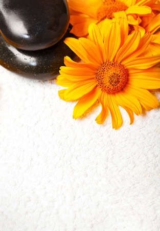 Spa stones on white towel with orange golden-daisy flowerの写真素材