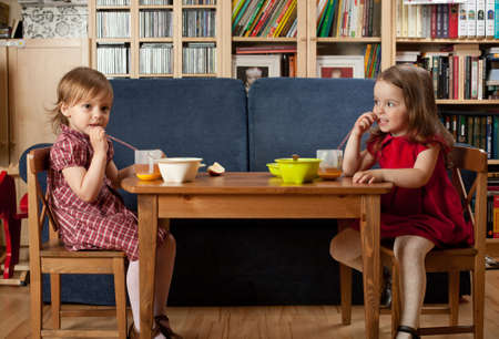 Two little smiling girls have a breakfast at homeの写真素材