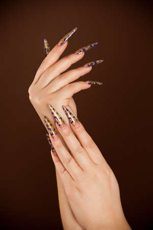 Hands with long fingernail and beautiful manicure isolated on brownの写真素材