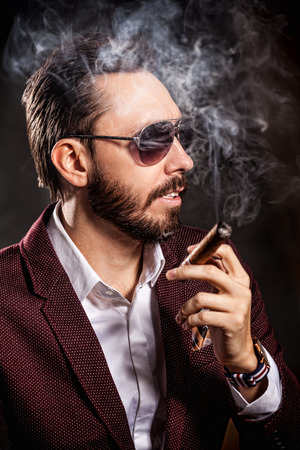 Portrait of handsome man in casual dress smoking a cigar の写真素材