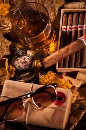 Time to relax! A complete set of male pleasures: a glass of whiskey, havana cigars in open humidor box, sunglasses and pocket watch in memory of a trip to Parisの写真素材