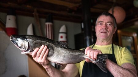 Ushuaia, Argentina - April 1 2019:  Sergio showing a big salmon. He is the owner of a little restaurant by the coast of Puerto Almanzaのeditorial素材
