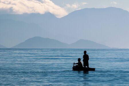 Ilha Grande, Brazil - March 20 2008: two brazilians black men rowing on the hurry in the middle of the sea, near to the coast of Abraao village.のeditorial素材