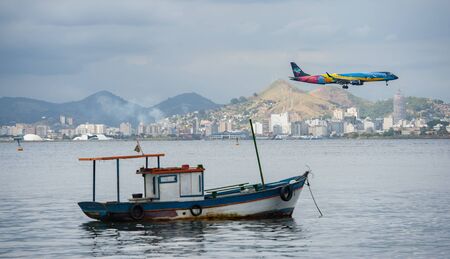 Rio de Janeiro, Brazil - August 17 2013: Fishing boat and comercial airplane Azul approaching to the airport Santos Dumontのeditorial素材