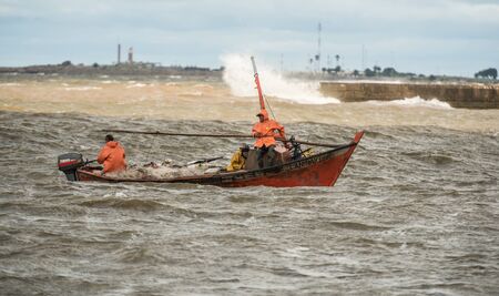 Montevideo, Uruguay - March 5 2016: Fishing boat and fishermen on the wild sea.のeditorial素材