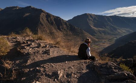 Pisac, Peru - August 11 2011: A man sitting on the edge of the mountain.のeditorial素材