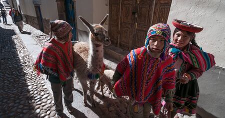 Cuzco, Peru - July 30 2011: Typical kids with a llama and a lamb in the street of Cuzco.のeditorial素材