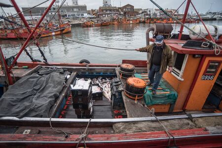 Mar del Plata, Argentina - September 19 2016: It is a small fishing boat, typical of the port of Mar del Plata, returning from a day of fishing, usually depart at dawn and return at sunset. He is the owner of the boat and had a very good day of fishing.のeditorial素材