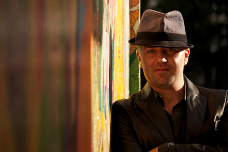 Sunlit man in hat beside colourful wallの写真素材