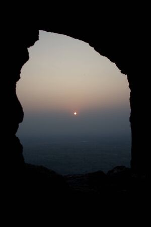 Sun on horizon in stone windowの写真素材