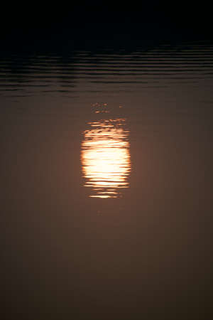 Reflection of setting sun in lakeの写真素材