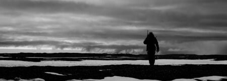 Black and white man hiking with rifleの写真素材