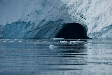 Cave in ice cliff in Arctic Oceanの写真素材