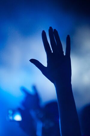 Hand of fan silhouetted against blue smoke