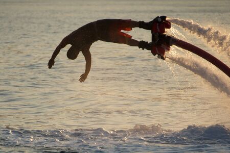 Close-up of diving Flyboarder backlit against wavesの写真素材