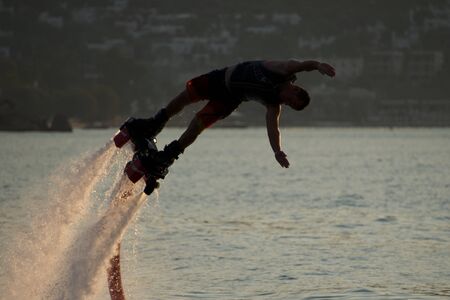 Close-up of Flyboarder diving into dusk seaの写真素材