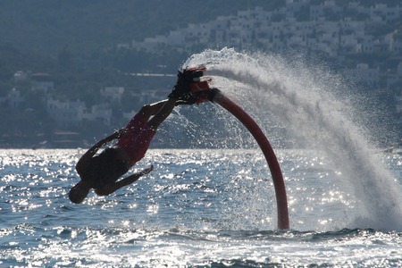 Flyboarder diving diagonally headfirst into backlit wavesの写真素材