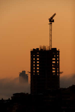 Dawn silhouette of office block with craneの写真素材