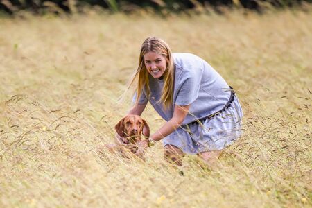 Woman holding Hungarian Vizsla in tall grassの写真素材