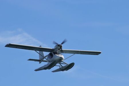 Hydroplane (seaplane or floatplane) flying in blue sky closeup. Cabin, wings propeller, engine, tail...