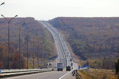 Highway in hills. Steep road running up and down. Cars in sunny day in autumn landscape. Road in the...