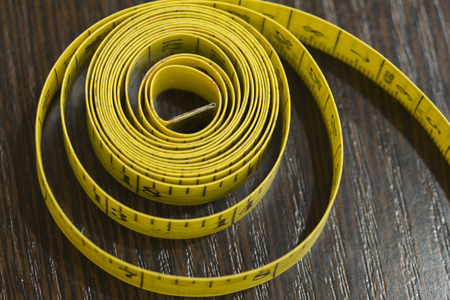 Close up tailor measuring tape on wooden table background. Yellow measuring tape shallow dept of...