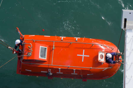 launching, lifting a lifeboat, two people leaned out of the hatch to release the hooksの写真素材