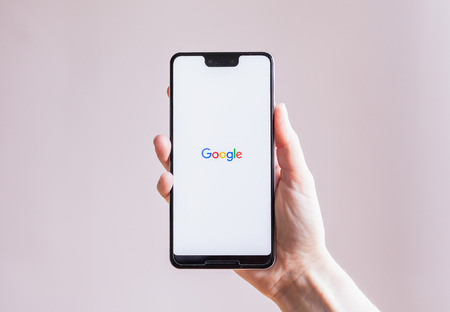 Hand holding Google Pixel 3 XL in front of plain backgroundのeditorial素材