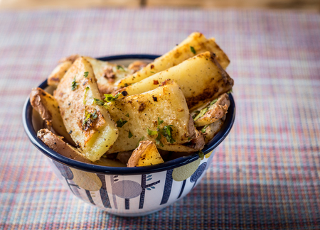 Delicious panfried chunky chips or fries garnished with parsley served in a pretty bowl in a rustic setting.の写真素材
