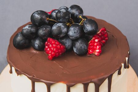 Delicious cake on a gray background. Decorated with grapes and pomegranateの写真素材