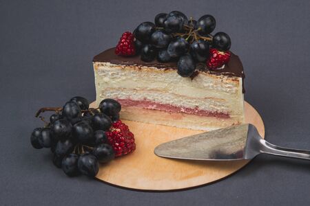 Delicious cake on a gray background. Decorated with grapes and pomegranateの写真素材