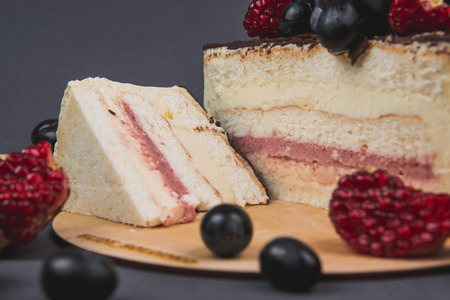 Delicious cake on a gray background. Decorated with grapes and pomegranateの写真素材