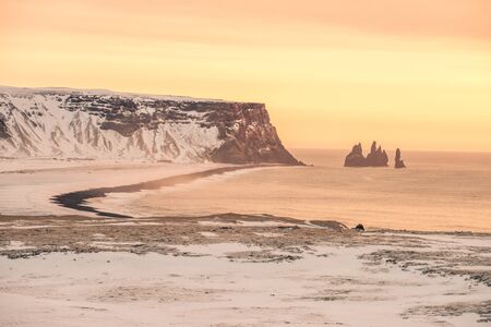 The sun sets on the snowy coast of Icelandの写真素材