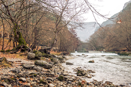 a river passes under a round bridge in zagorohoria greeceの写真素材