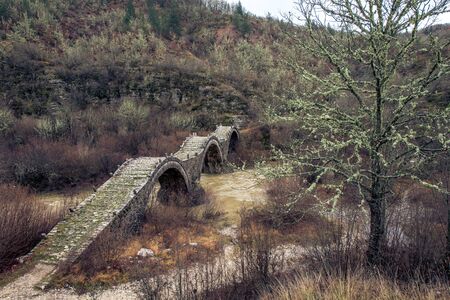 round bridges cross a river in zagorohoria greeceの写真素材