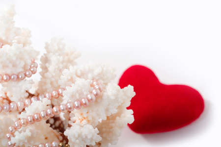 pearl beads, corals and red velvet heart on white background with copy space in the top right corner. Focal point is on the pearls, heart is out of focus.の写真素材