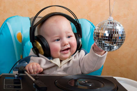 baby with headphones playing with turntable and disco ballの写真素材