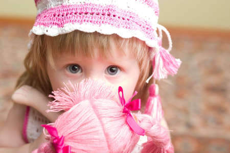 cute little girl with doll in her hands looking into the cameraの写真素材