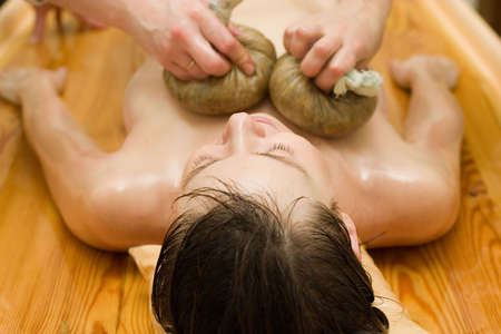 ayurvedic therapy: massage procedure with oil and pouch of rice and spicesの写真素材